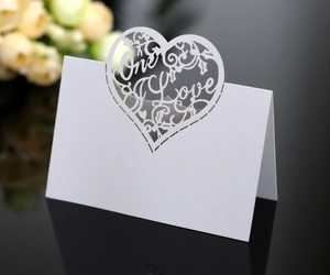 Detail of laser-cut heart seat card with One Love text and elegant lace pattern