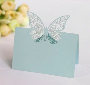 Macro detail of a laser-cut light blue butterfly place card with intricate floral patterns