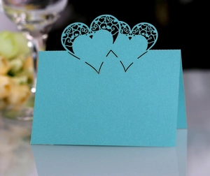 Detail of teal heart laser-cut place card with elegant scrollwork for weddings