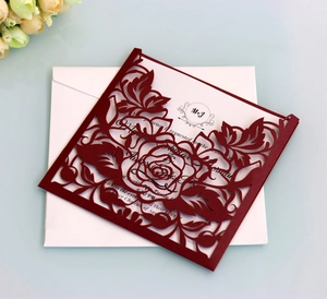 Detailed laser-cut burgundy rose patterns on elegant wedding invitation cards