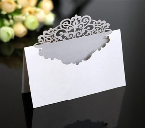 Macro shot of white laser-cut lace place cards on a black mirror surface for weddings