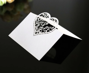 Close-up of laser-cut heart place card with Only Love lettering on reflective surface