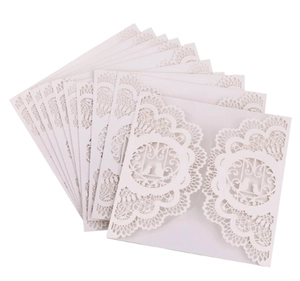 Detail of laser-cut wedding invitations with intricate lace birds and floral patterns