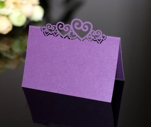 Detail of purple pearlescent place card with laser-cut heart crown on black mirror