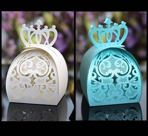 Detail of laser-cut wedding candy boxes with heart patterns and crown-shaped handles