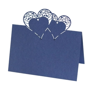Detail of laser-cut navy blue heart place card with intricate lace patterns for weddings