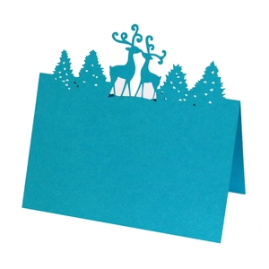 Detail of blue laser-cut reindeer and pine tree place card with elegant folding design