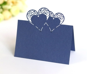 Detail of dark blue laser-cut place card with three hollow heart patterns and V-fold design