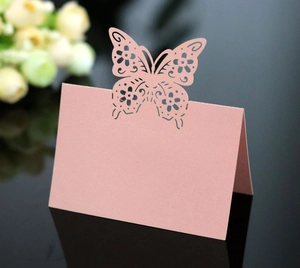Detail of pink laser-cut butterfly place card for wedding with elegant hollowed pattern
