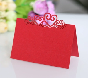 Macro view of red laser-cut heart pattern on hollow V-shaped wedding table seat card