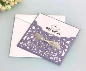 Macro view of lavender lace laser-cut invitation with grey silk bow and inner card