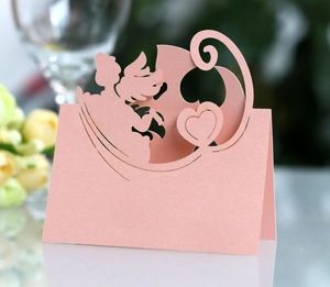 Detailed laser-cut angel design on pink pearlescent paper wedding place cards