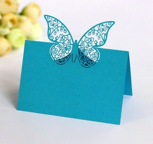 Macro detail of laser-cut peacock blue butterfly place card with floral hollowed patterns