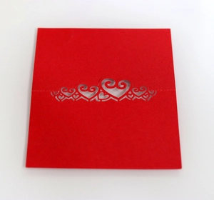 Close-up of red laser-cut place card featuring intricate heart pattern for weddings