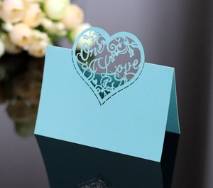 Detail of light blue laser-cut heart place card with One Love text and vine patterns