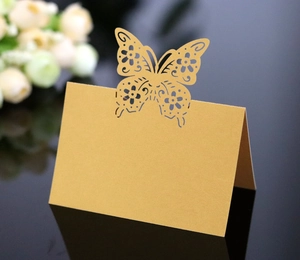 Detail of laser-cut gold butterfly place card with elegant hollow pattern for weddings
