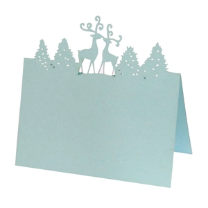 Detail of laser-cut light blue Christmas place card with reindeer and pine forest silhouettes
