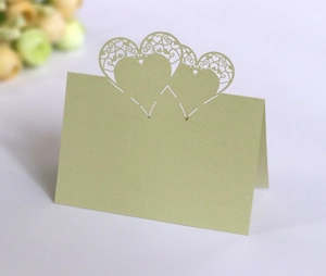 Close-up of laser-cut light green place card featuring intricate hollow heart patterns