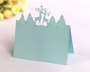 Detail of laser-cut light blue reindeer and pine tree silhouette table cards for Christmas