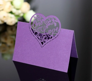 Detail of purple laser-cut One Love heart table card with glitter texture for weddings