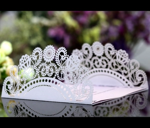 Macro detail of laser-cut white wedding invitation featuring intricate floral lace patterns