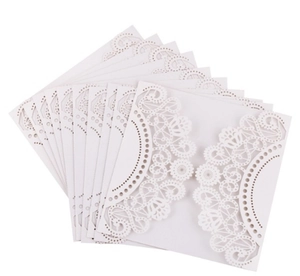 Macro shot of white laser-cut rose invitations with intricate lace patterns for weddings