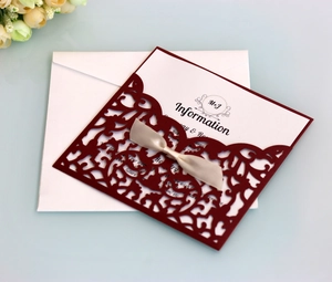 Macro detail of laser-cut burgundy wedding invitation with elegant champagne bow and insert