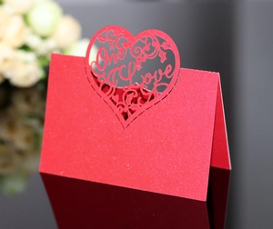 Detail of red glitter wedding place card featuring laser-cut heart and One Love text