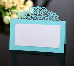 Macro view of laser-cut lace wedding place card with elegant blue pattern and white insert