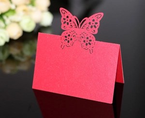 Macro detail of red glitter laser-cut butterfly place card with floral hollow pattern