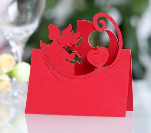 Macro detail of red laser-cut wedding place card featuring Cupid and heart patterns