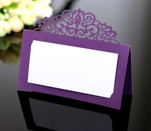 Detail of purple laser cut lace wedding place card with white insert on black surface