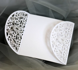 Detail of white laser-cut floral wedding invitation cover with intricate hollow patterns
