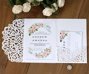 Close-up of laser-cut rose hollow wedding invitation with RSVP card on wood background