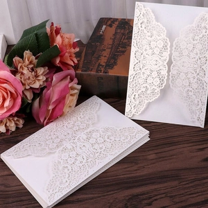 Elegant laser-cut white rose lace wedding invitation pocket on vintage wood table