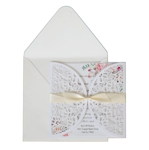 Intricate laser-cut floral wedding invitation set with ivory envelope and silk ribbon bow