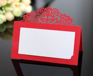Detailed view of red laser-cut lace place card for weddings on black reflective surface