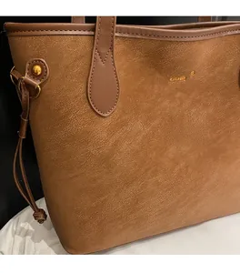 Close-up of brown pebbled leather tote bag with gold logo and side drawstring detail
