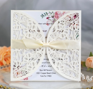 Detail of ivory laser-cut floral wedding invitation with an elegant silk ribbon bow