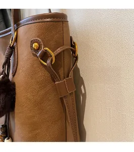 Detailed macro of dark brown leather texture with golden ring hardware and plush ball charm