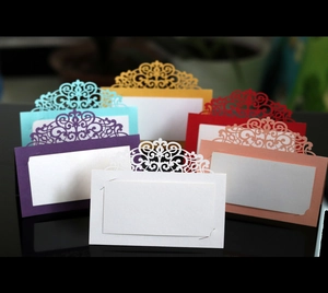 Detailed laser-cut lace patterns on multi-colored wedding place cards with a mirror reflection