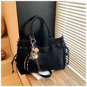 Detail of matte black tote bag with side drawstring and leopard print tassel charm