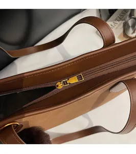 Close-up of golden zipper and stitching on caramel brown leather tote bag with Matisse book