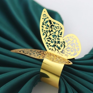 Golden 3D butterfly napkin ring with hollow floral pattern on green fabric