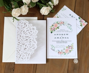 Elegant laser cut white rose wedding invitation suite with cards on dark wood background