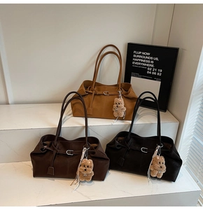 Detailed view of suede tote bags in brown and black with cute bear charms on marble stairs
