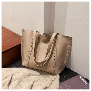 Close-up of beige lychee grain leather tote bag with silver metal rivet detail