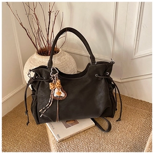 Detail shot of black slouchy tote bag with leopard bow and heart charm in a lifestyle setting