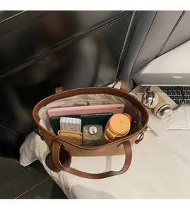Brown leather tote bag showing spacious interior with tablet, water bottle and notebooks