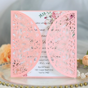 Detail of pink laser-cut wedding invitation with floral inner card on glass tray